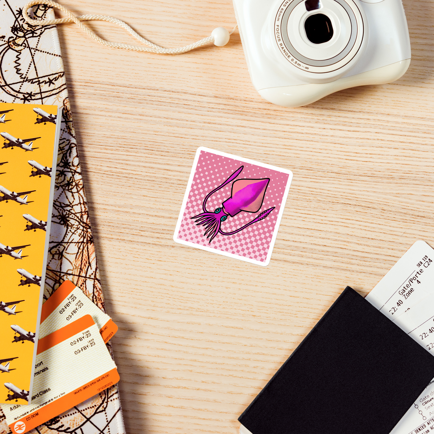 Loligo Vulgaris Squid pop art magnet 3x3 — pink and magenta squid on a checkered halftone background placed on a wooden surface with a camera and other items.