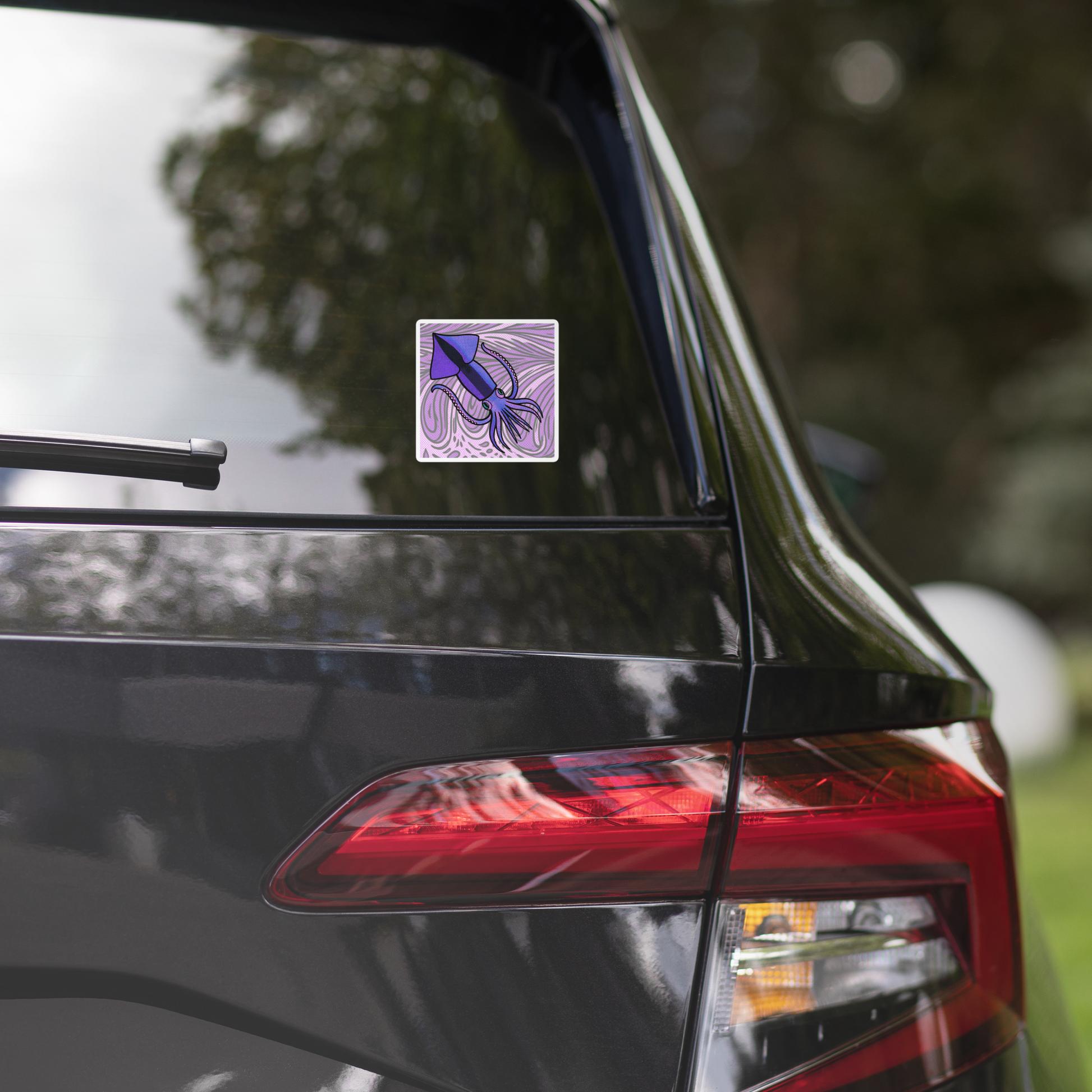 Car with a Loligo Todarus Squid pop art vinyl sticker 4x4 — purple squid on lavender swirl halftone background on the rear window, surrounded by greenery.