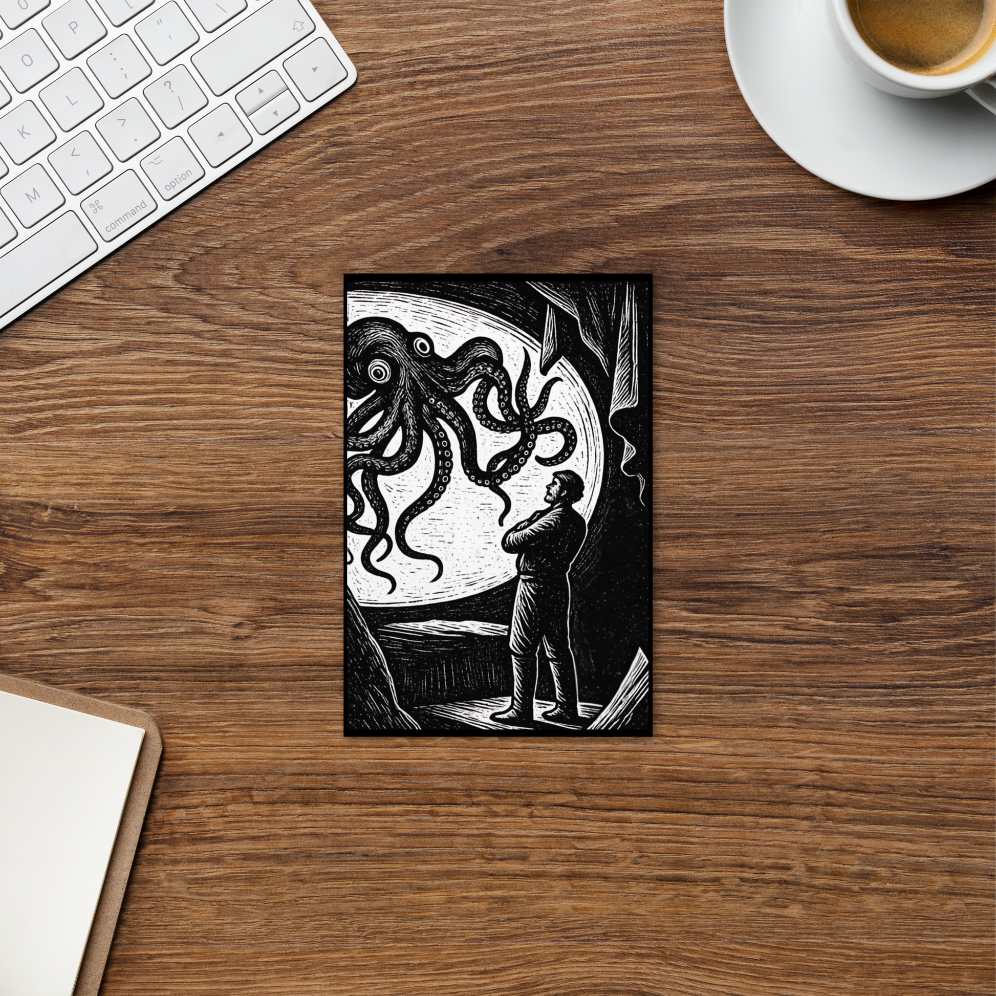 Desk with 20,000 Leagues Under the Sea lithocut postcard — black and white giant squid scene from Jules Verne illustration, a keyboard, and a coffee cup.